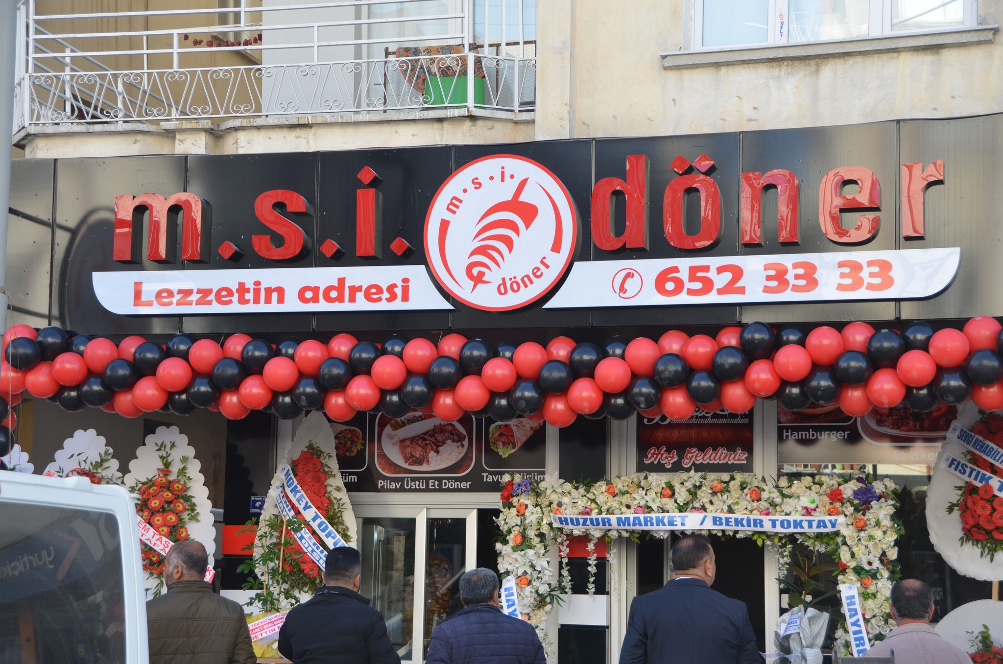 Bir 4 kişi ve şunu diyen bir yazı 'm.s.i. Lezzetin adresi döner döner 652 33 33 Pilav Üstü Döner Tavu Hoợ Geldiniz TOPI HUZUR MARKET ন BEKİR TOKTAY' görseli olabilir